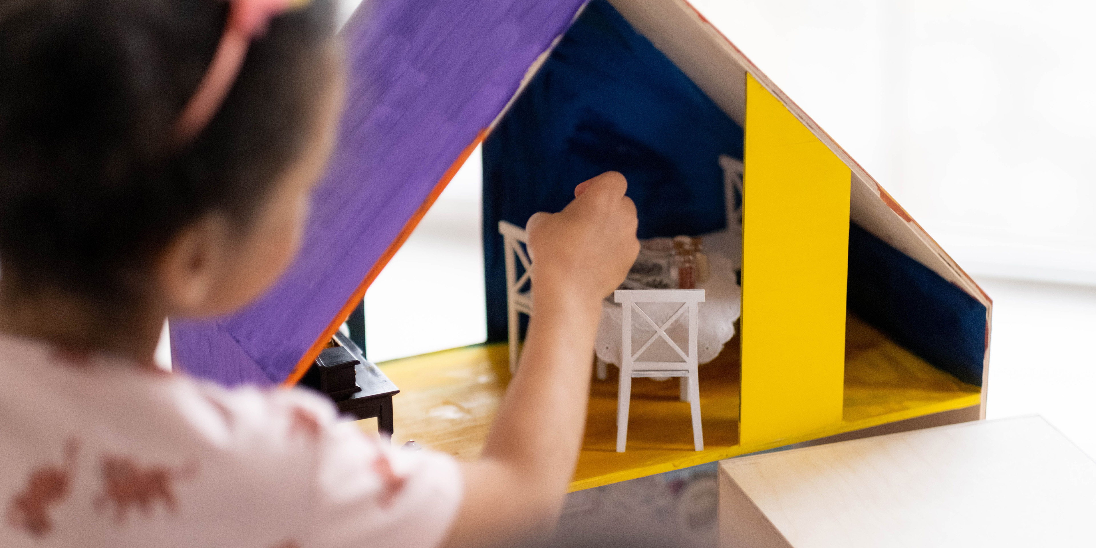 Das Bild zeigt ein Kind. Das Kind baut ein Modellzimmer.