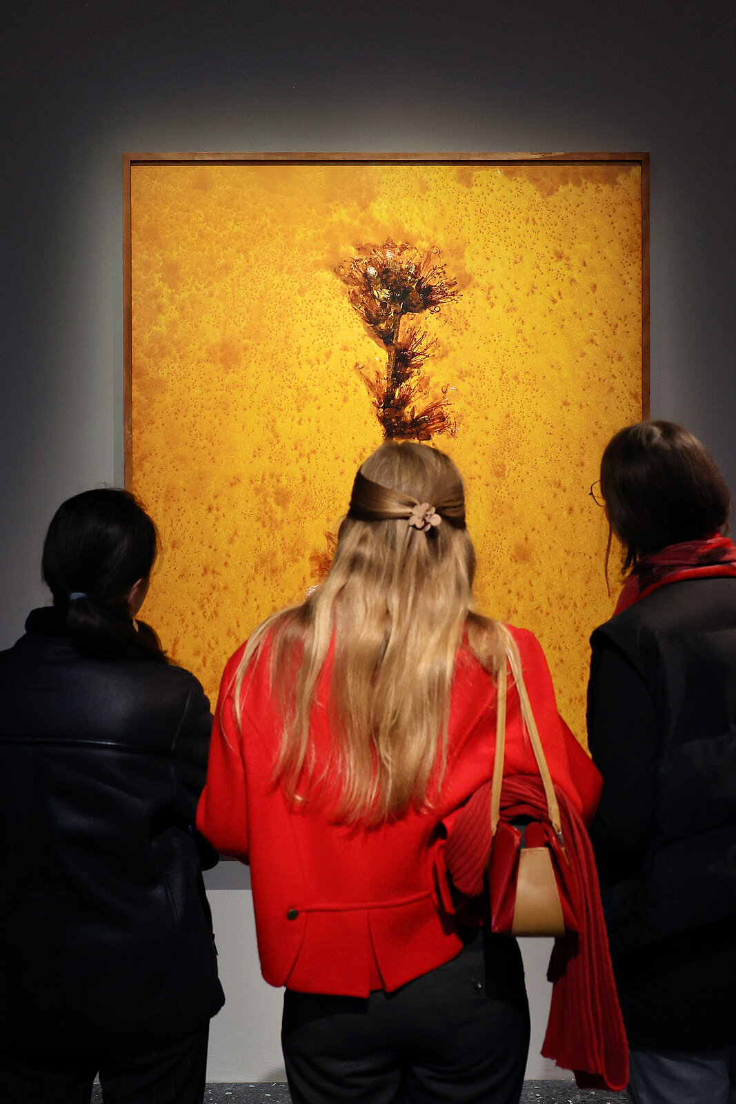 Auf dem Bild sind 3 Personen im Ausstellungraum zu sehen. Sie schauen sich ein Gemälde an.